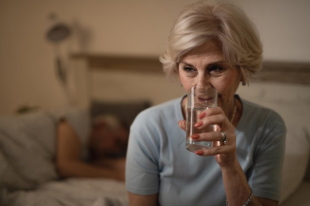 Free photo sleepless mature woman having a glass of water in bedroom