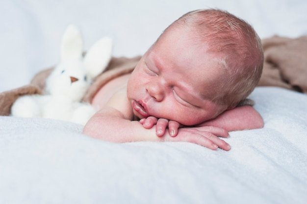 Free photo sleepy baby with toy rabbit