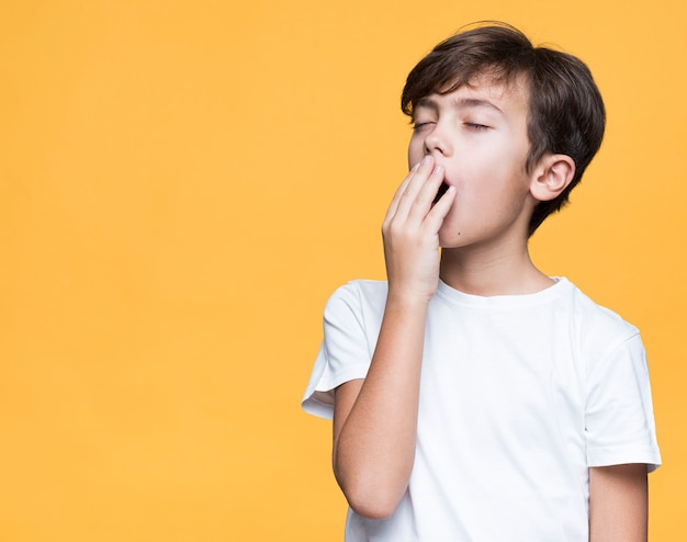 Sleepy young boy on yellow background