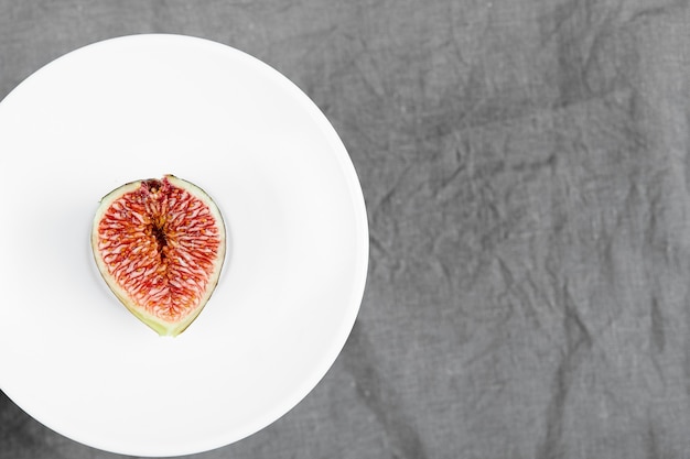 Free photo a slice of black fig on a white plate. high quality photo