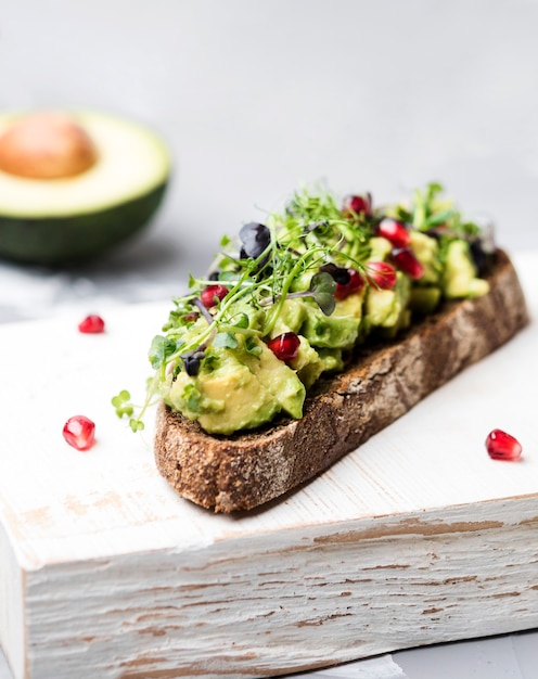 Slice of bread with avocado pasta and veggies close-up