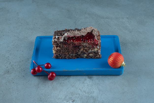 Slice of cake and christmas baubles on a platter on marble surface