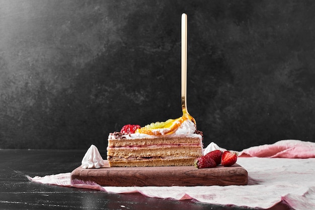 Slice of cake with berries on wooden platter.