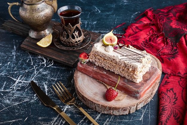 Free Photo a slice of cake with a glass of tea on a wooden board. 