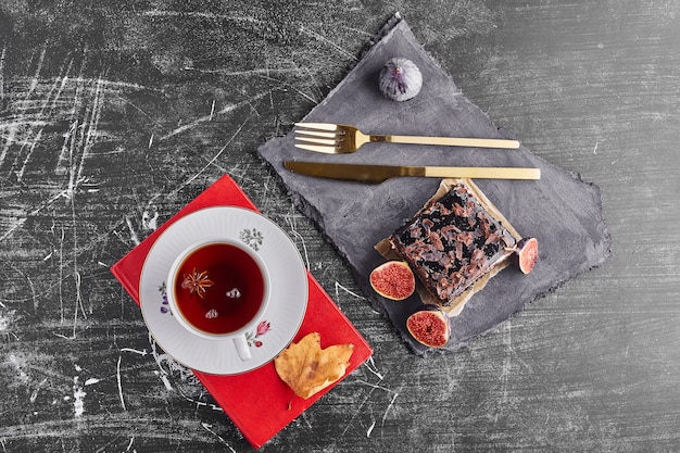 A slice of chocolate cake with figs and tea, top view. 