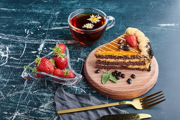 A slice of chocolate cake on a wooden board. 