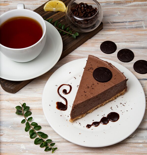 A slice of chocolate mousse cheesecake with chocolate chips and a cup of tea. 