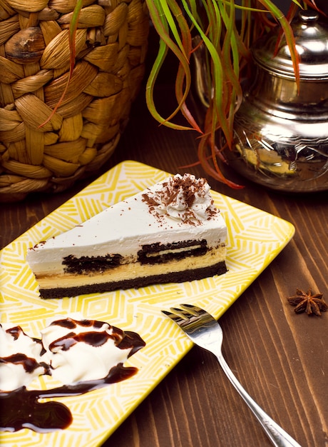 Slice of chocolate vanilla cheesecake on plate against a rustic brown wood table 