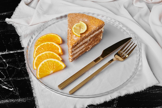 Free photo a slice of honey cake with orange slices.