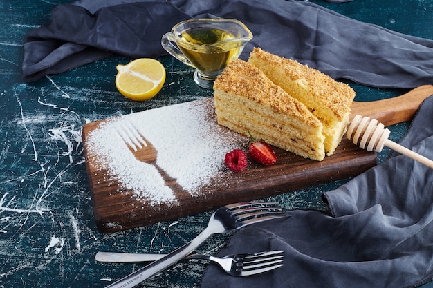 Free photo a slice of honey cake on a wooden board.