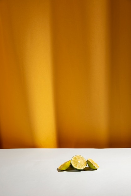 Slice of limes on white table in front of yellow curtain