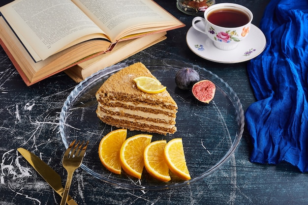 A slice of medovic cake with citrus fruits and tea. 