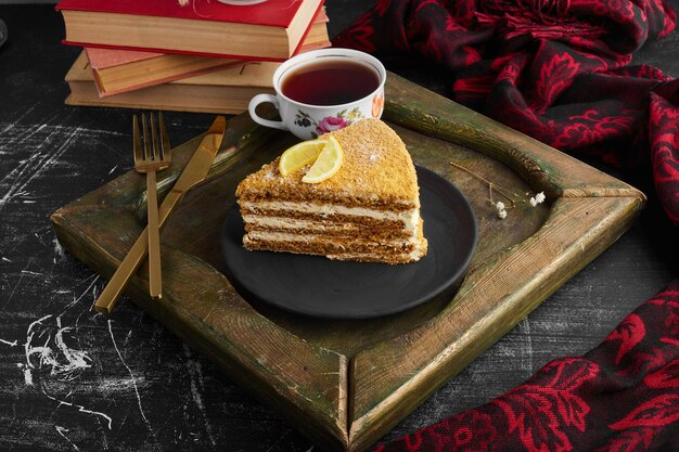 A slice of medovic cake with lemon and tea. 