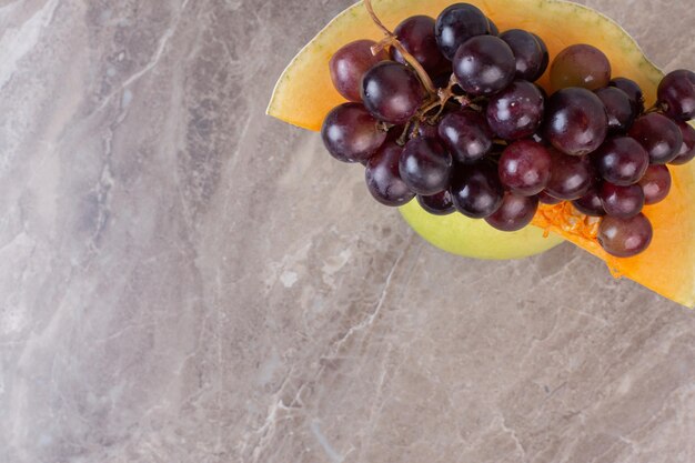 A slice of pumpkin and grapes on marble surface.