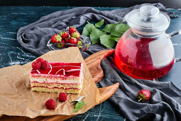 A slice of strawberry cheesecake with a jar of juice. 