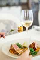 Free photo slice of a tasty tuna meal with glass of white wine at the restaurant