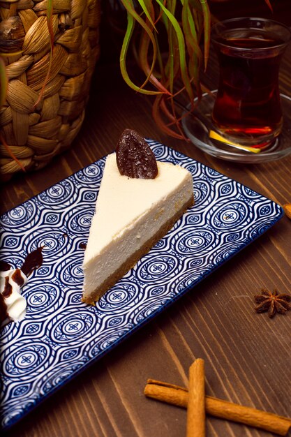 Slice of vanilla cheesecake on plate against a rustic brown wood table