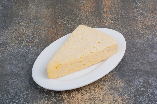 Slice of yellow cheese on white plate