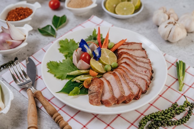 Sliced ÃÂÃÂ¢ÃÂÃÂÃÂÃÂÃÂÃÂ¢ÃÂÃÂÃÂÃÂfried pork with lemon, onion, red onion, tomato, long bean, butterfly pea flower, and mint.