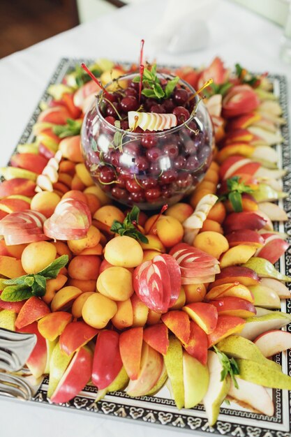 Sliced apples, peaches, peers served on large mirror