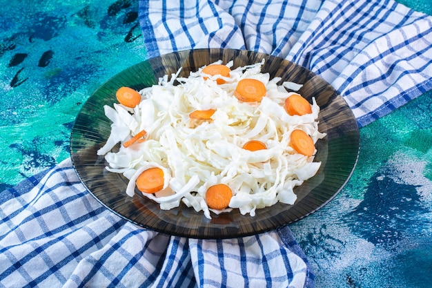 Sliced cabbage and carrots in a plate on a tea towel