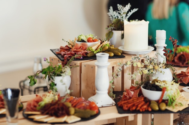 Sliced cheese and meat served on plate with olivas stand on wooden boxes