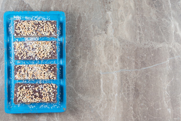 Free Photo sliced chocolate bar with nuts on wooden plate on marble.