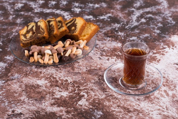 Free Photo sliced cocoa pie with cookies in a glass platter with a glass of tea