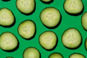 Free photo sliced cucumber pattern on a green background