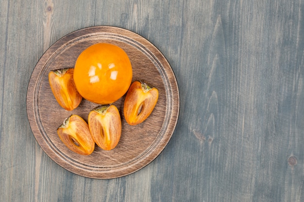 Sliced delicious persimmon in a wooden plate