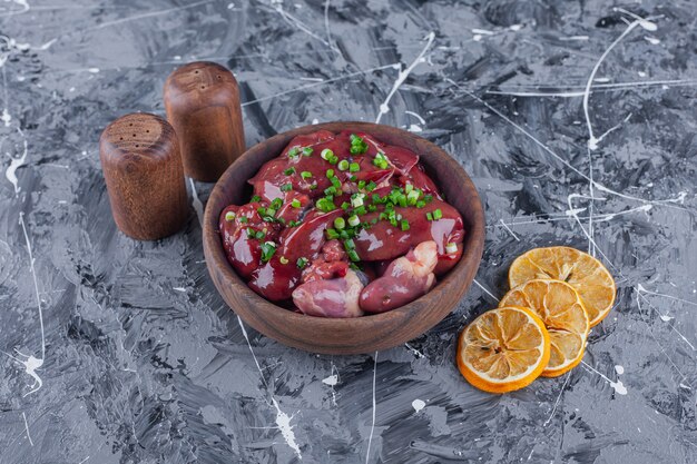 Sliced dried lemons and offal in a bowl on the blue surface