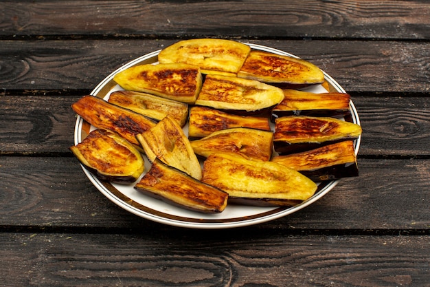 Free Photo sliced eggplants fried tasty on a round plate and rustic wooden desk