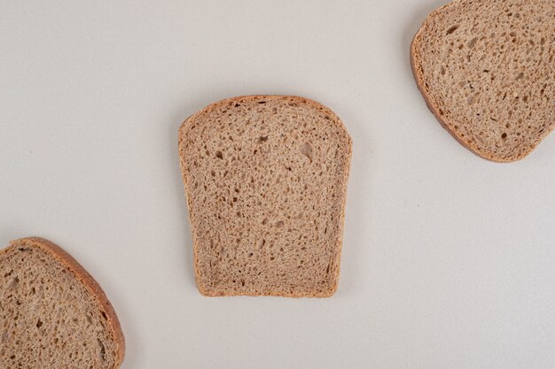 Sliced fresh brown bread on white surface