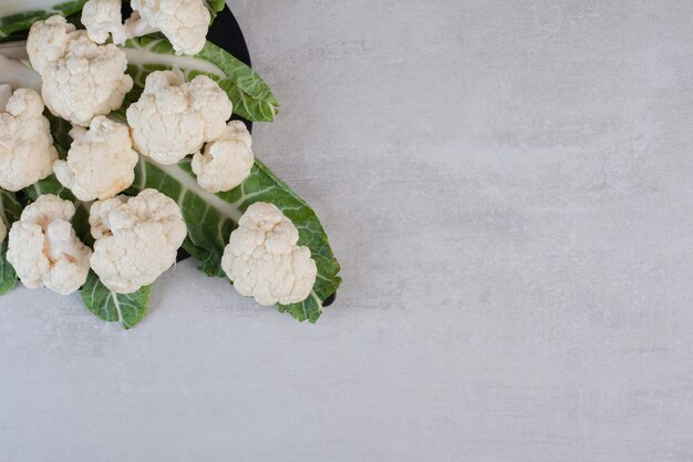 Sliced fresh cauliflower with leaves on black board. High quality photo