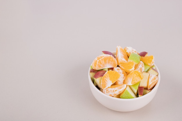 Sliced fresh fruits in white bowl.