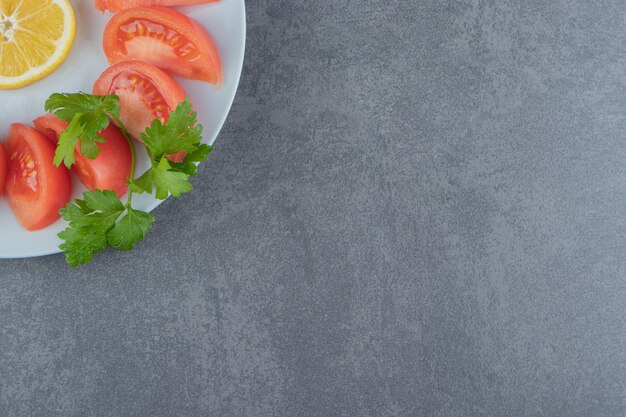 Sliced fresh tomatoes and parsley on white plate.