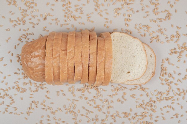 Sliced fresh white bread with oat grains on white surface