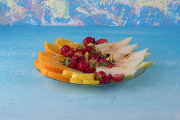 Sliced fruit set in a glass platter isolated on blue space