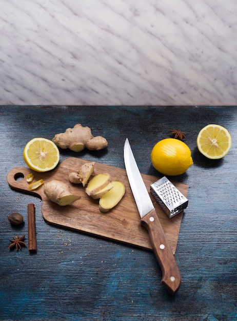 Sliced ginger on wooden board with lemon on table