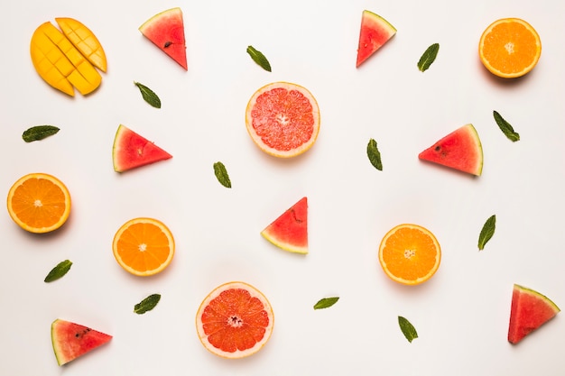 Free photo sliced grapefruit watermelon orange mango and green leaves