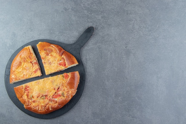 Free photo sliced homemade pizza on black cutting board.