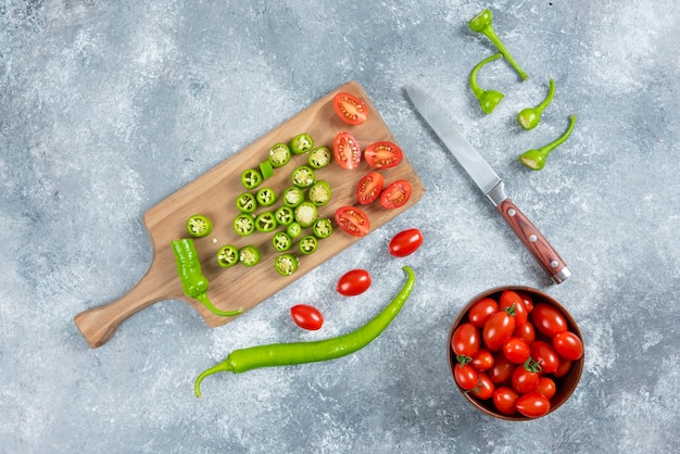 Free photo sliced jalapeno peppers and tomatoes on wooden board.