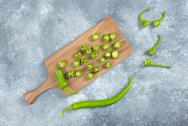 Sliced jalapeno peppers on wooden board.