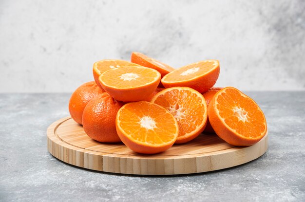 Sliced juicy fresh orange fruits in a wooden plate .