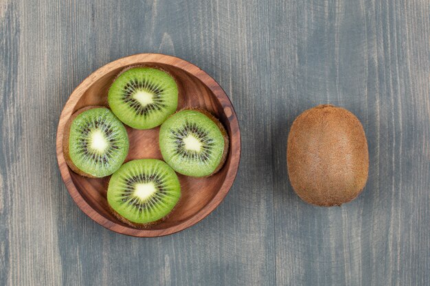 Sliced kiwi with whole kiwi on a wooden table