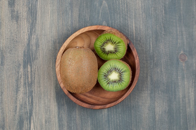 Sliced kiwi with whole kiwi on a wooden table