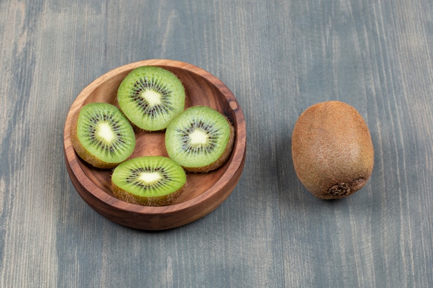 Sliced kiwi with whole kiwi on a wooden table