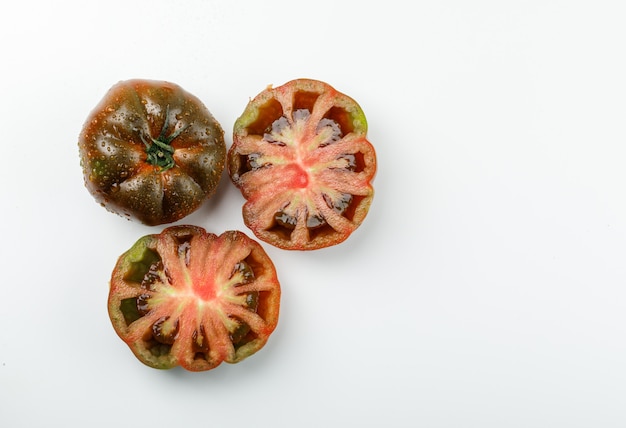 Sliced kumato tomato on a white wall. flat lay.