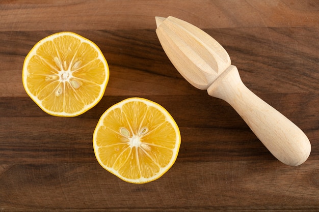 Free photo sliced lemon with a wooden reamer on a wooden table.