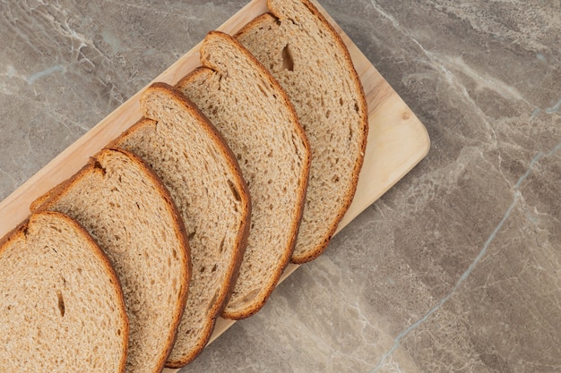 A sliced loaf of brown bread on a stone surface